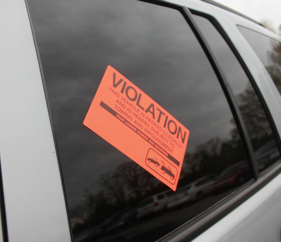 Bright orange stickers are being placed on cars due to violation of parking rules. The number of violation stickers places on cars has gone up since the removal of the Career Center lot. 