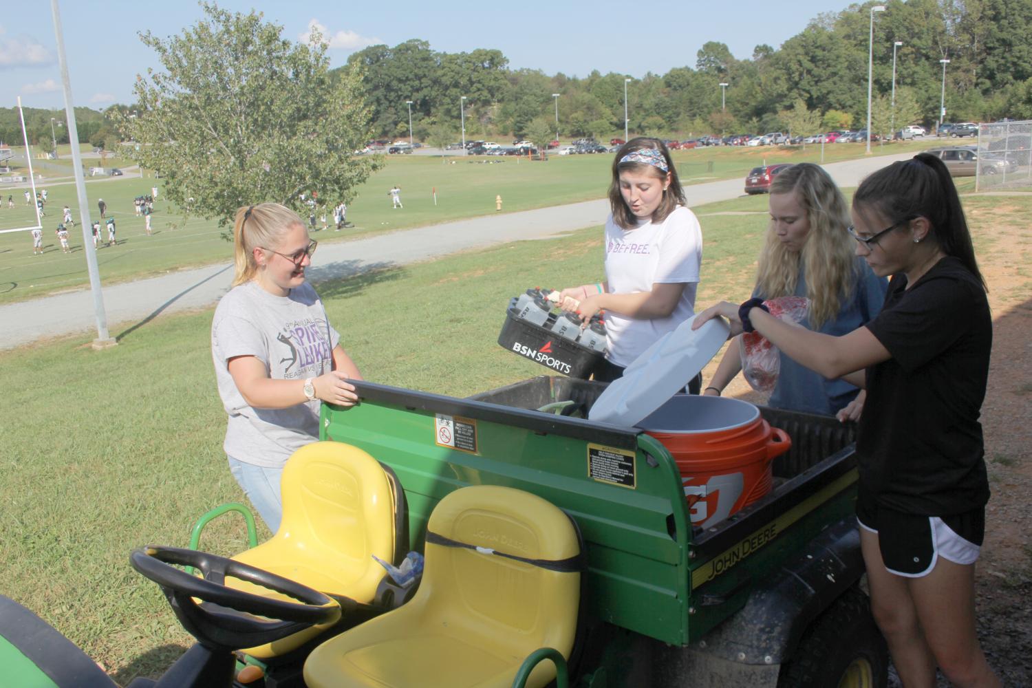 (From left to right) Senior Alyssa Taylor, juniors Hannah Bryan and Sam Dembosky, and sophomore Michelle Salus load the Gator with materials for football practice. Salus is the only returning trainer from last year.