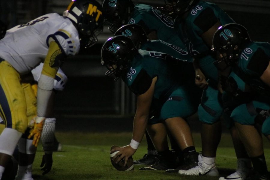 The center (#56), Jake Pascal sets up to make the snap at the Friday Night LIghts Game versus Tabor.