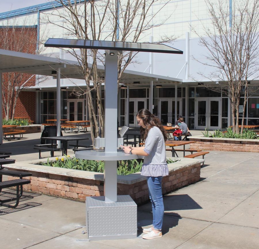 Senior Haylie Paulin, charges her phone on the new solar charing panels. Science teacher Ed Thutt won the solor panel by applying for a grant.