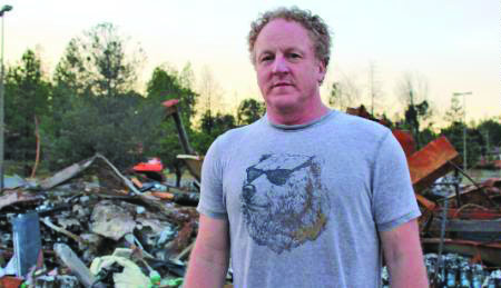 Woody Faircloth stands amidst the wreckage of the Camp Fires. He donated over 70 RVs to victims.