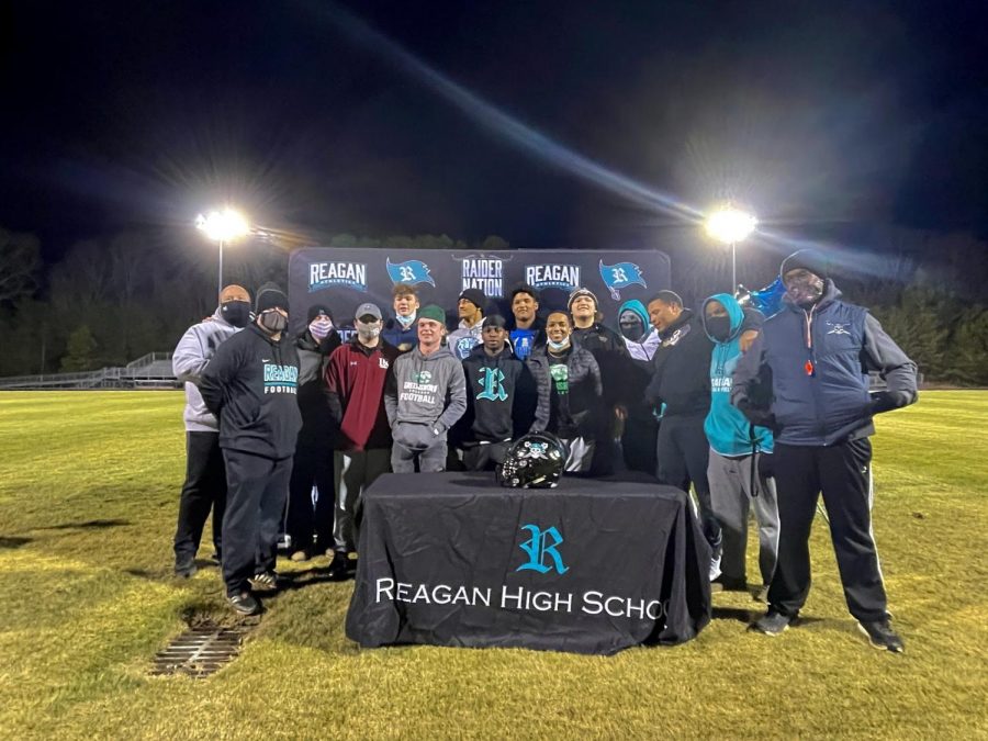Reagan+seniors+on+the+football+team+join+together+with+their+head+coaches+after+signing.+The+senior+class+of+2021+is+the+first+group+to+sign+for+colleges+in+all+levels+of+collegiate+athletics.
