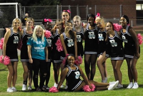 The varsity cheer team poses alongside coach Saleen Gardner after cheering at a game. Though it is Gardners first season, the team has grown a very close bond.